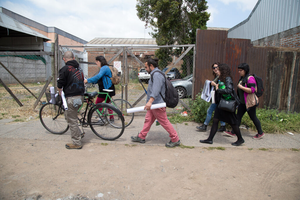 Grupo de personas con bicicletas y a pie con carteles en las manos caminando por zona industrial de Curicó.